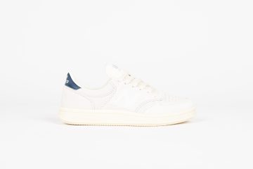 New Balance Der <b><i>New Balance T500</i></b>, der für die Freizeit wieder eingeführt wurde, behält den klassischen Charme des Originals von 1982. Er besteht aus hochwertigem Schweinswildleder und Nubukleder mit perforierter Zehenpartie und verfügt über eine Fischgräten-Außensohle mit Drehkreis, eine Zwischensohle aus Polyurethan und ein konturiertes Fußbett. Die überwiegend weiße Farbgebung und das ‘New Balance’-Branding an der Ferse runden das Design ab. “Shell White/Sail / Navy” (CT500NVA)