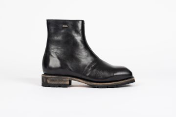 Our Legacy Der <b><i>Our Legacy Engine Boot</i></b> in tiefschwarzem Leder verkörpert feine Handwerkskunst und zeitlosen Stil. Aus hochwertigem italienischem Leder gefertigt, verfügt dieser knöchelhohe Stiefel über eine robuste <i>Vibram-Laufsohle</i> für erhöhte Haltbarkeit und Traktion. Ein Lampo-Seitenreißverschluss sorgt für einfaches Anziehen, während eine metallene Our Legacy-Niete eine unverkennbare Note verleiht. Das Leder, sorgfältig ausgewählt, trägt natürliche Unvollkommenheiten, die jedem Paar einen einzigartigen, authentischen Look verleihen, der sich mit der Zeit auf wunderbare Weise entwickelt. Die <i>Kilger</i>-Lederzwischensohle, bezogen aus Deutschland, trägt zum luxuriösen und widerstandsfähigen Aufbau des Stiefels bei. “Black Leather” (A4247EDB)
